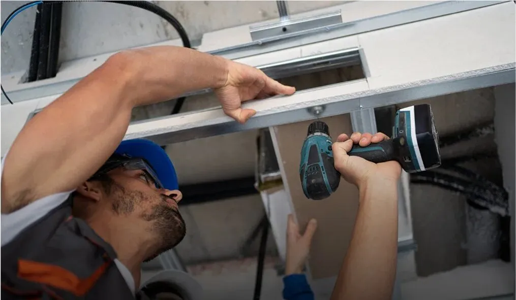 Technician installing a fixture with a drill