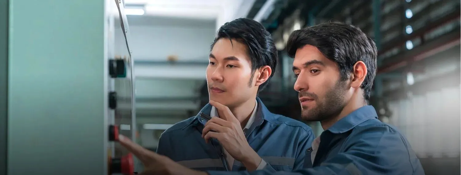 Two technicians checking an equipment panel